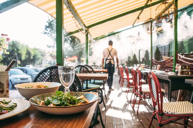 Outdoors summer terrace cafe with served table and waiter. If pests infest your business, Batzner Pest Control is here to help.